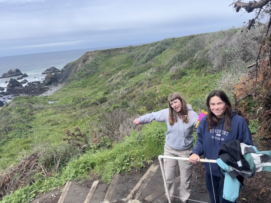 Two people with survey equipment on a coastal trail