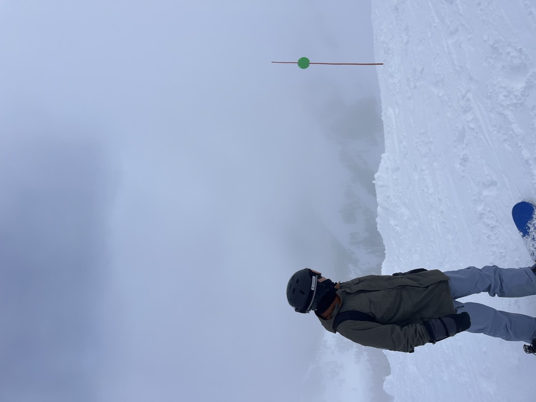 Standing with a snowboard on a slope in heavy fog